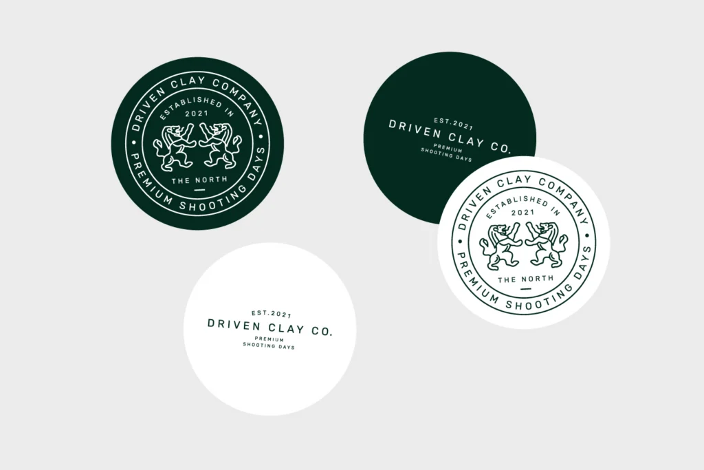 Four round Driven Clay Co. stickers in forest green and white, showing the lion crest badge and the wordmark