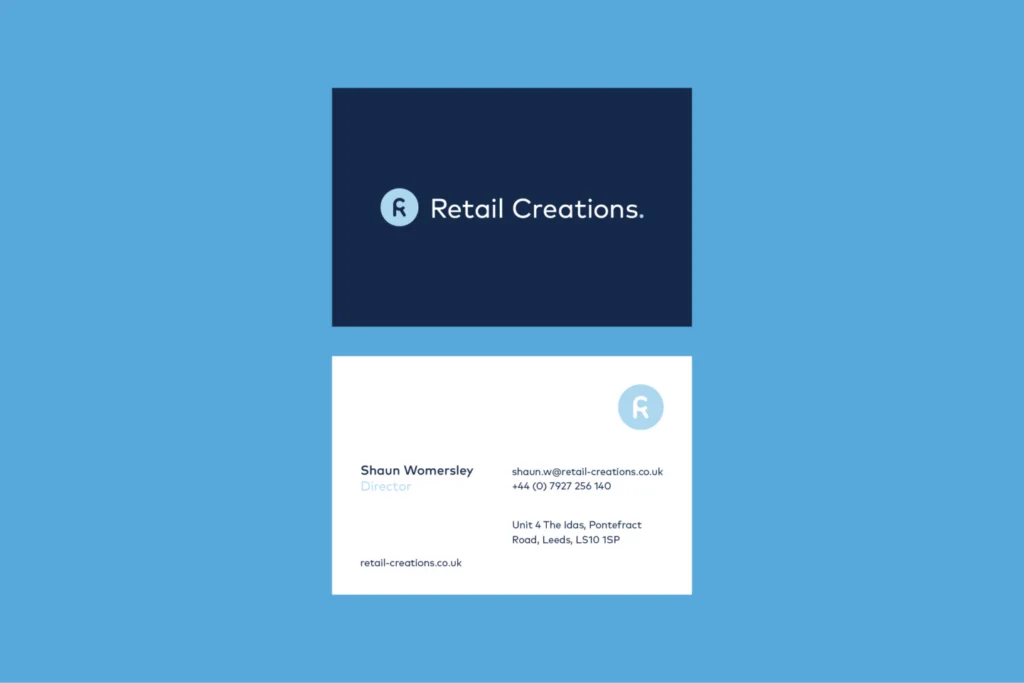 Retail Creations business cards: navy front with the logo, white back with the brandmark and contact details, on blue