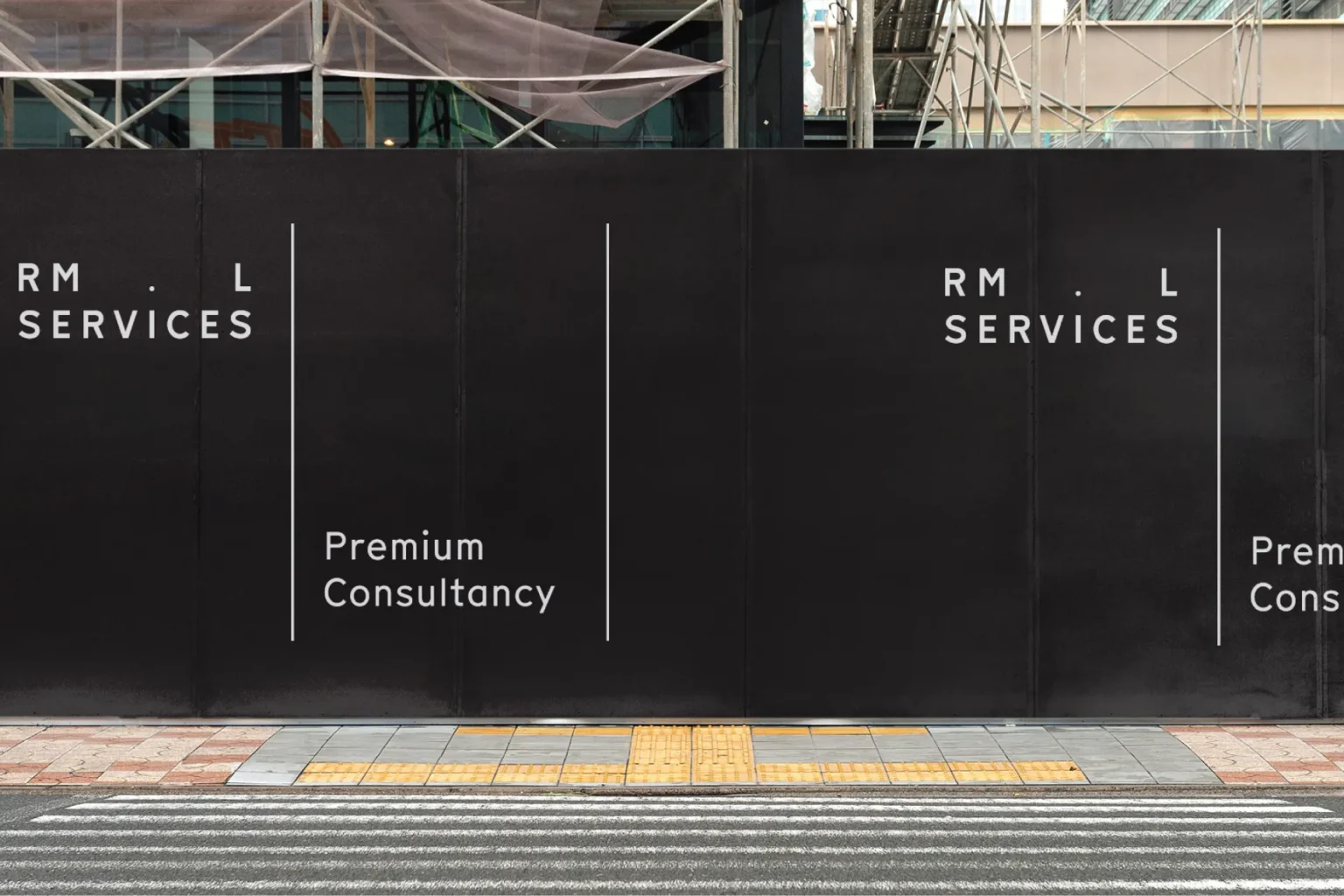 RML Services black construction site hoarding with the white wordmark and 'Premium Consultancy', beside a crossing