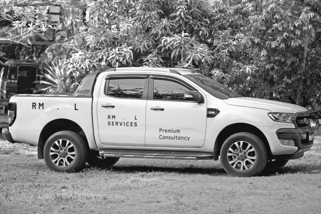 RML Services livery on a white pickup truck, with the wordmark and 'Premium Consultancy' on the doors, in black and white