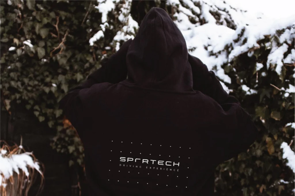 Sportech Motorsport hoodie back print: the Driving Experience logo and dot grid on black, against snowy ivy