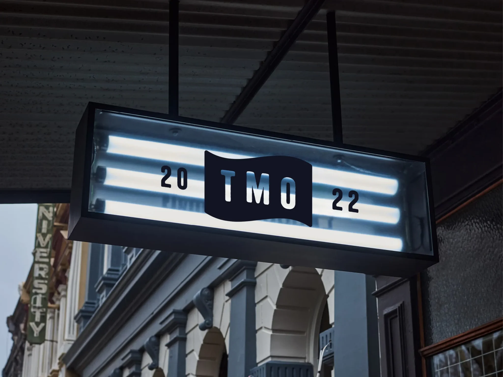 The Mad Ox hanging lightbox sign with the TMO flag badge and 20 22, under a shopfront canopy