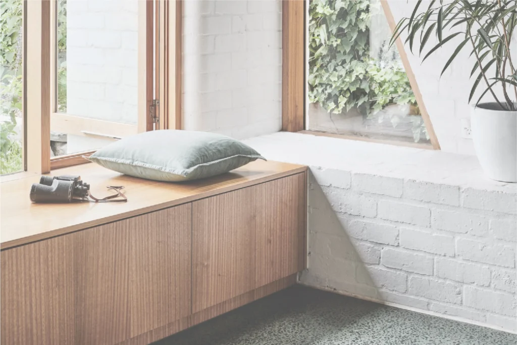 Williams Joinery photography: timber window seat with a cushion and binoculars beside a white-painted brick wall